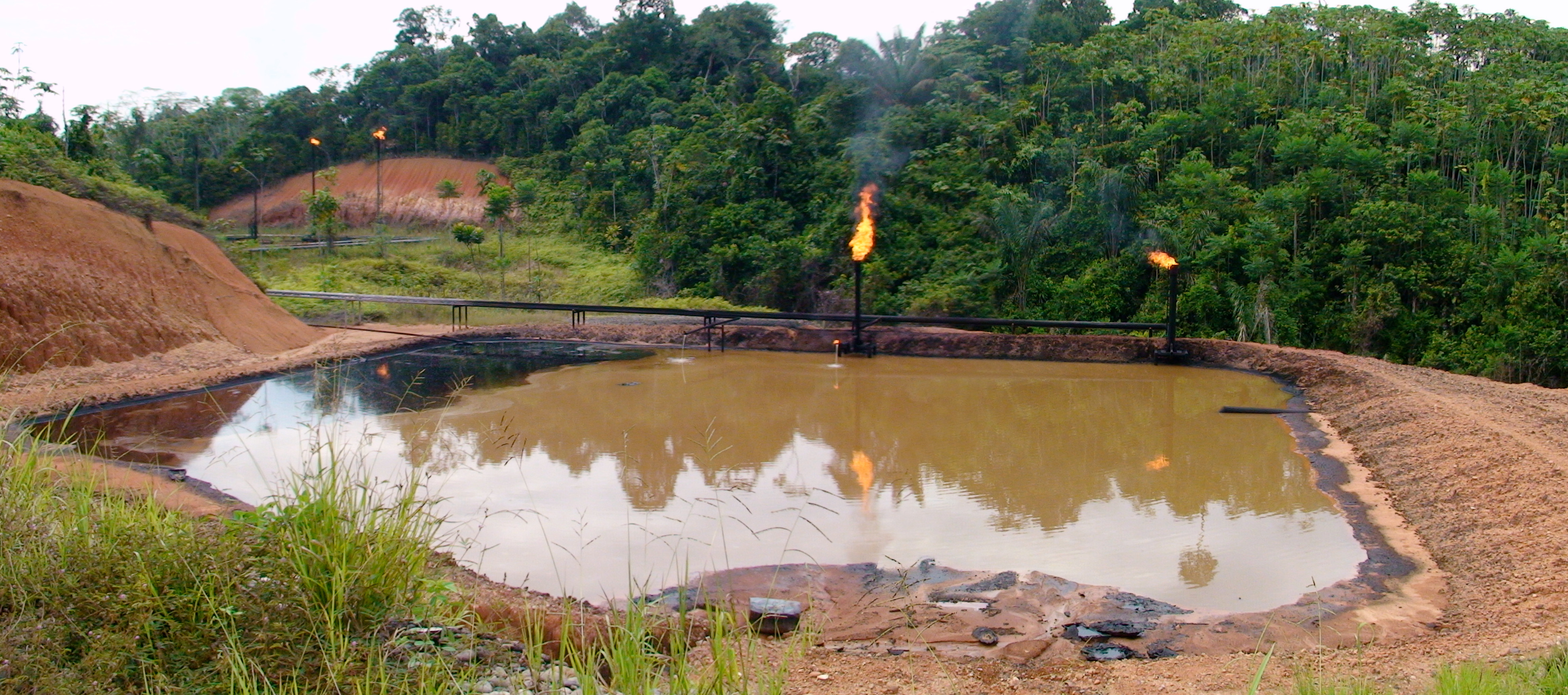 Gas flare over waste oil and water pit